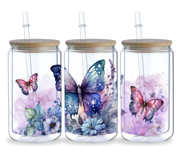 Drei 16 oz Glasbecher mit Bambusdeckel und Glastrinkhalm, verziert mit detailreichen Schmetterlings- und Blumenmotiven in Blau-, Lila- und Rosatönen. Die kunstvollen Illustrationen bringen einen Hauch von Natur und Eleganz in jedes Getränk.